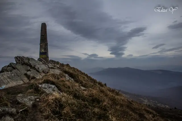 Кам’яний знак на вершині гори Пікуй над хвилястими карпатськими хребтами