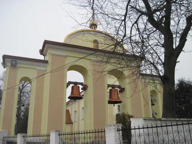 Аркова дзвіниця в Зарваниці з підвішеними дзвонами, за нею — золочена баня храму