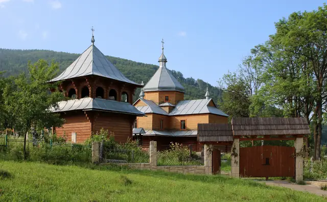 Дерев’яна церква Успіння Пресвятої Богородиці в Яремчі на тлі лісистого схилу